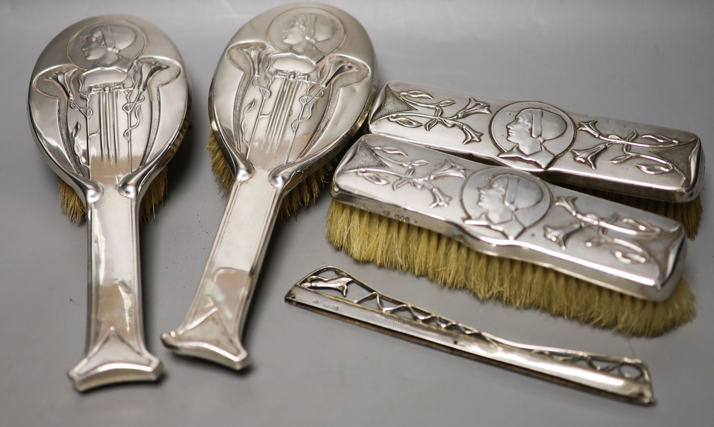 An Edwardian Art Nouveau silver mounted brush and comb set (a.f.), by William Hutton & Sons, London, 1904(4) and Birmingham, 1907(1), largest 24.6cm